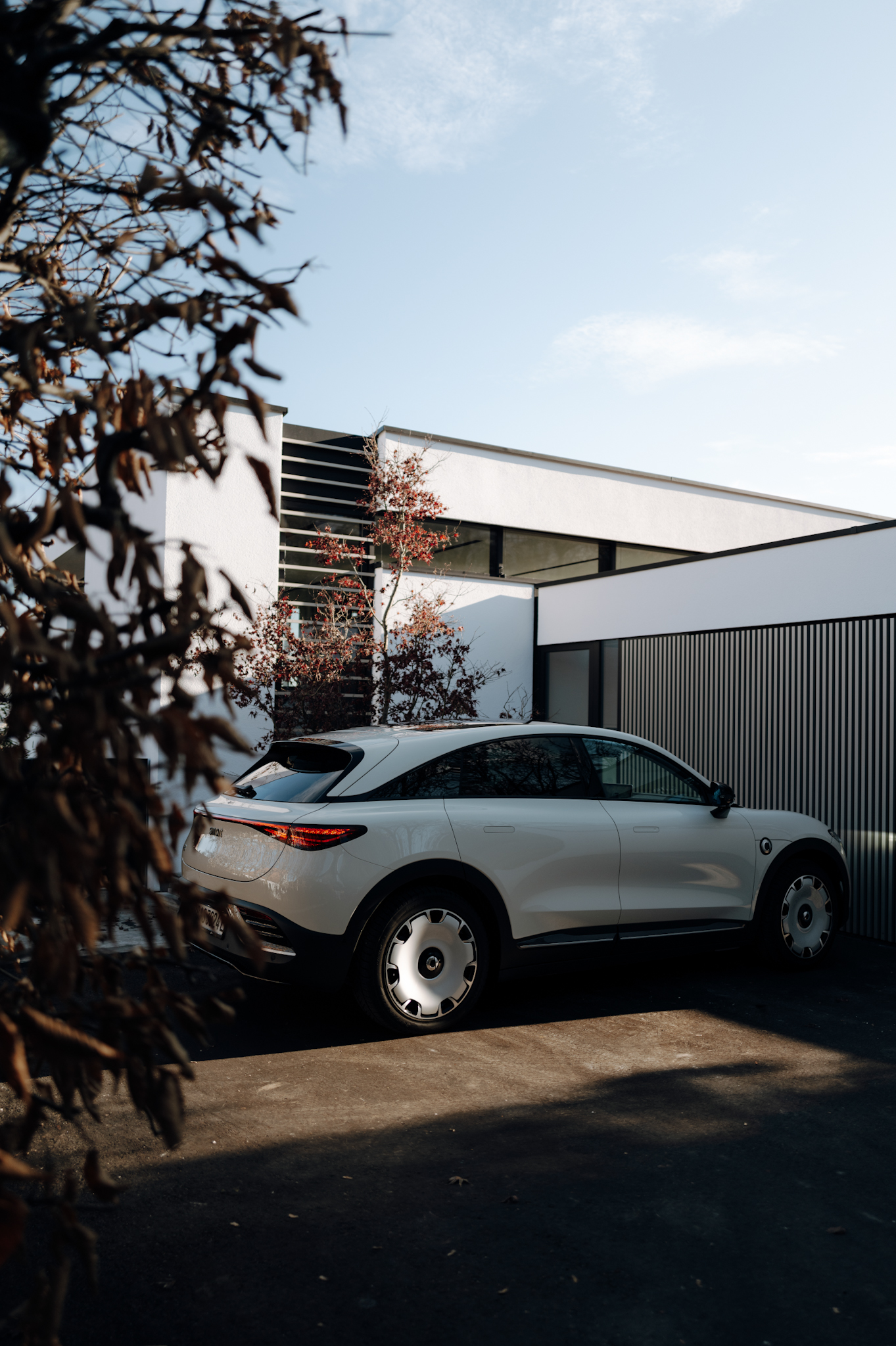 Smart #3 Premium in Ceramic Cream parked in front of modern architecture with autumn details.