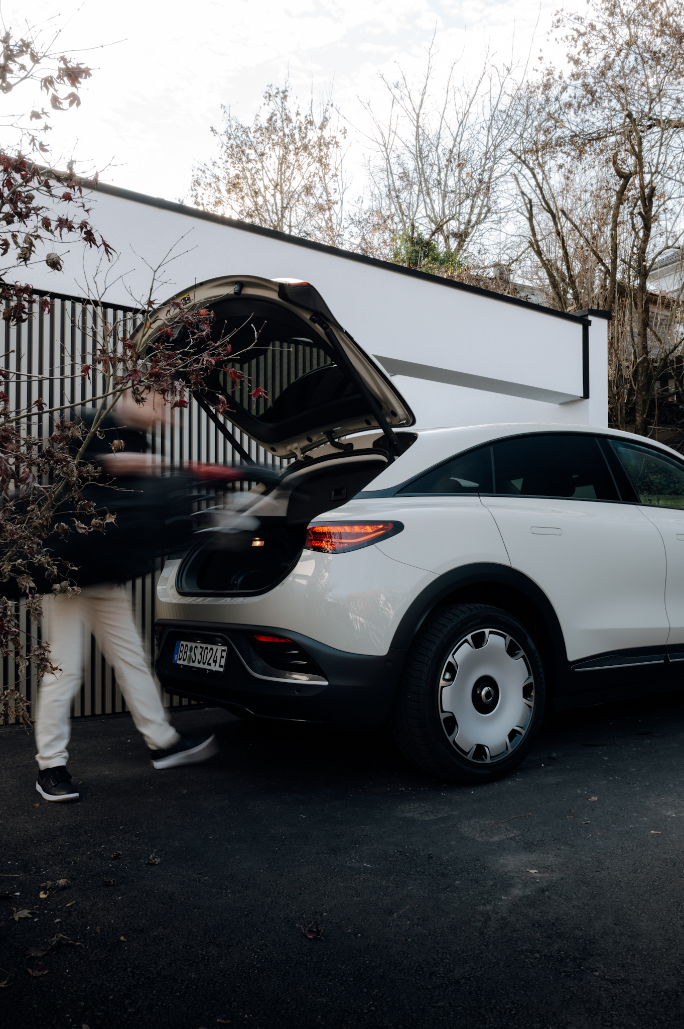 Man loading golf bag into the trunk of a Smart #3 Premium in Ceramic Cream.