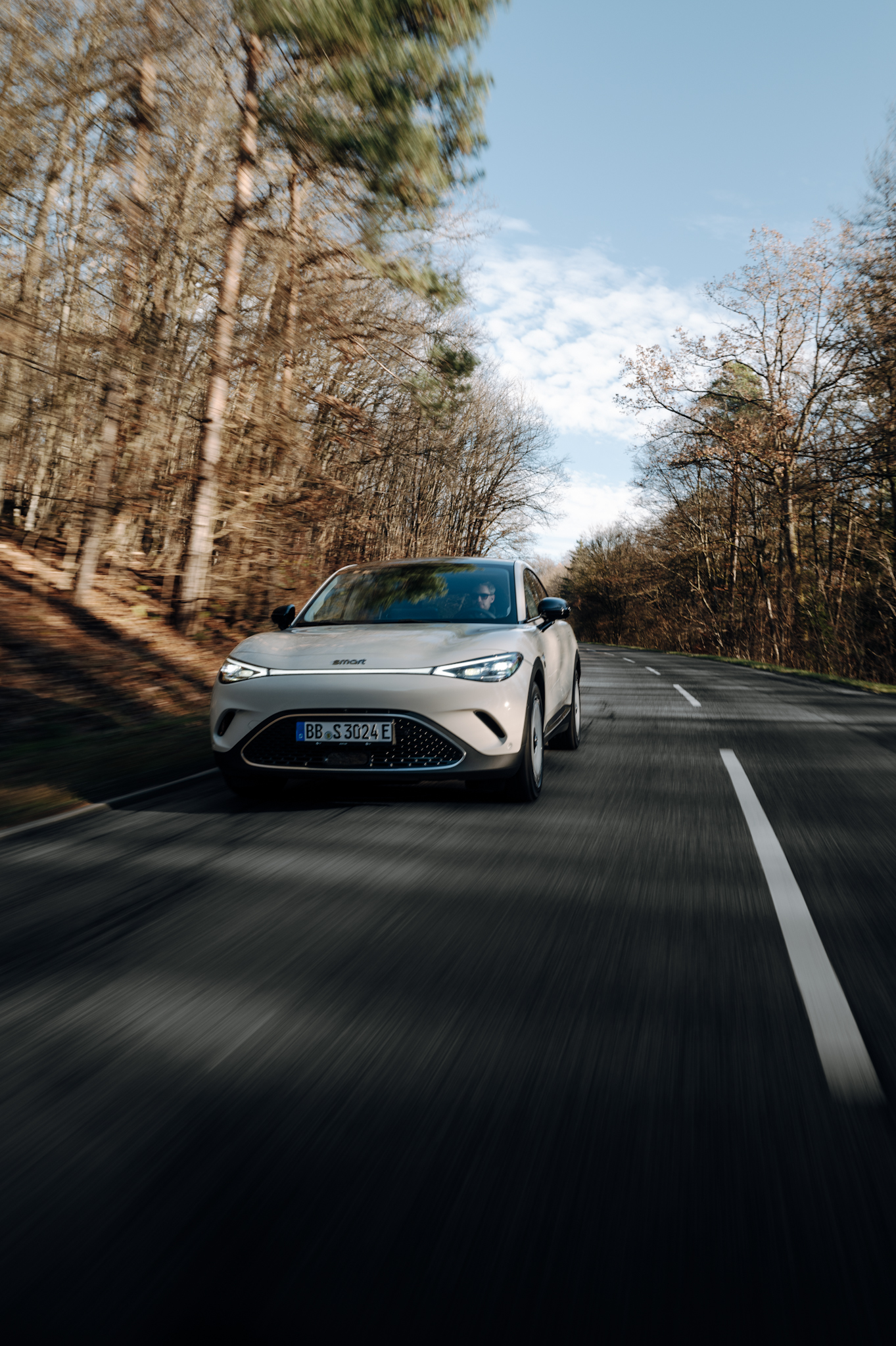 Smart #3 Premium driving on a scenic road surrounded by trees.