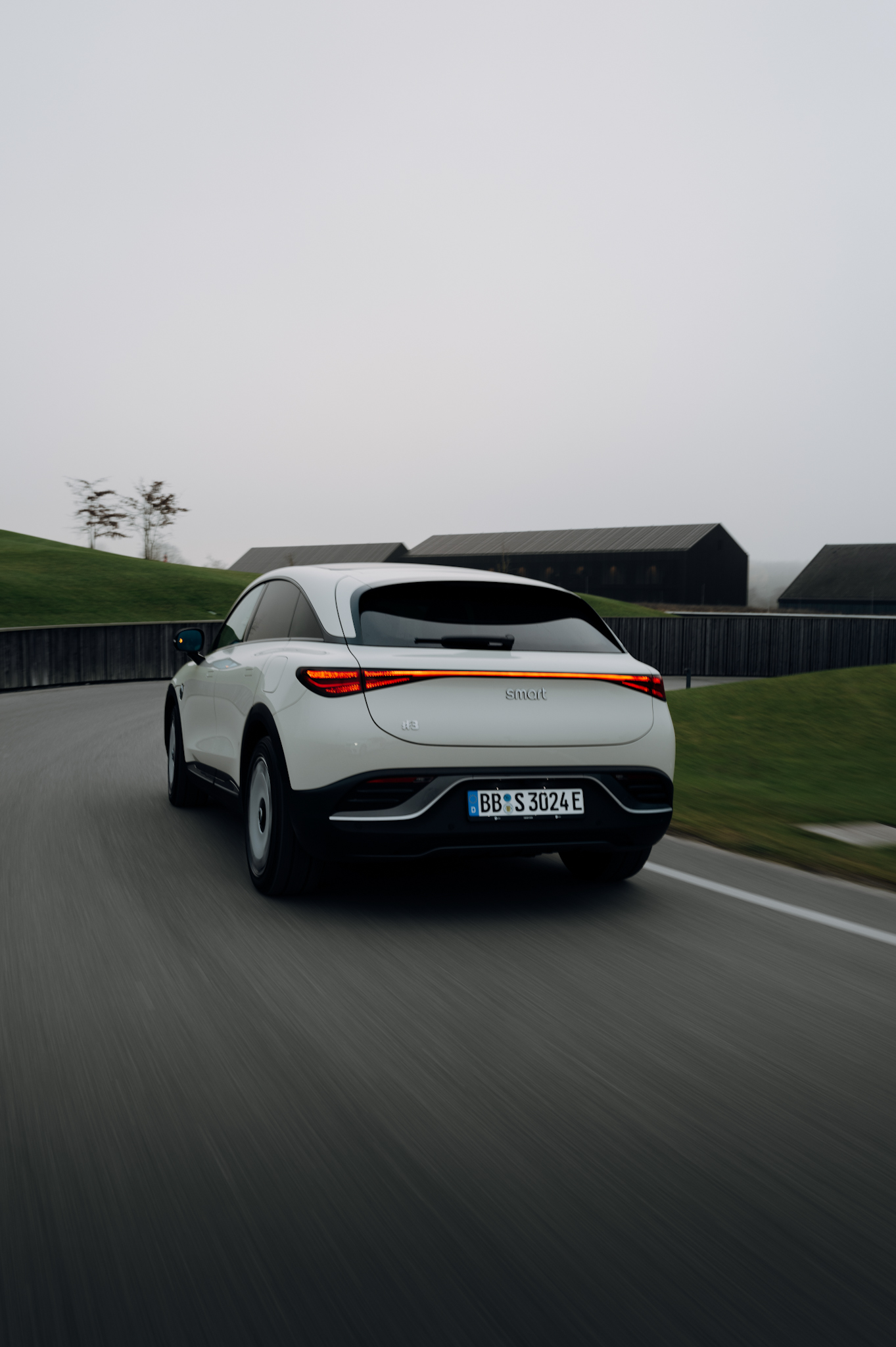 Rear view of Smart #3 Premium driving near a modern golf resort.