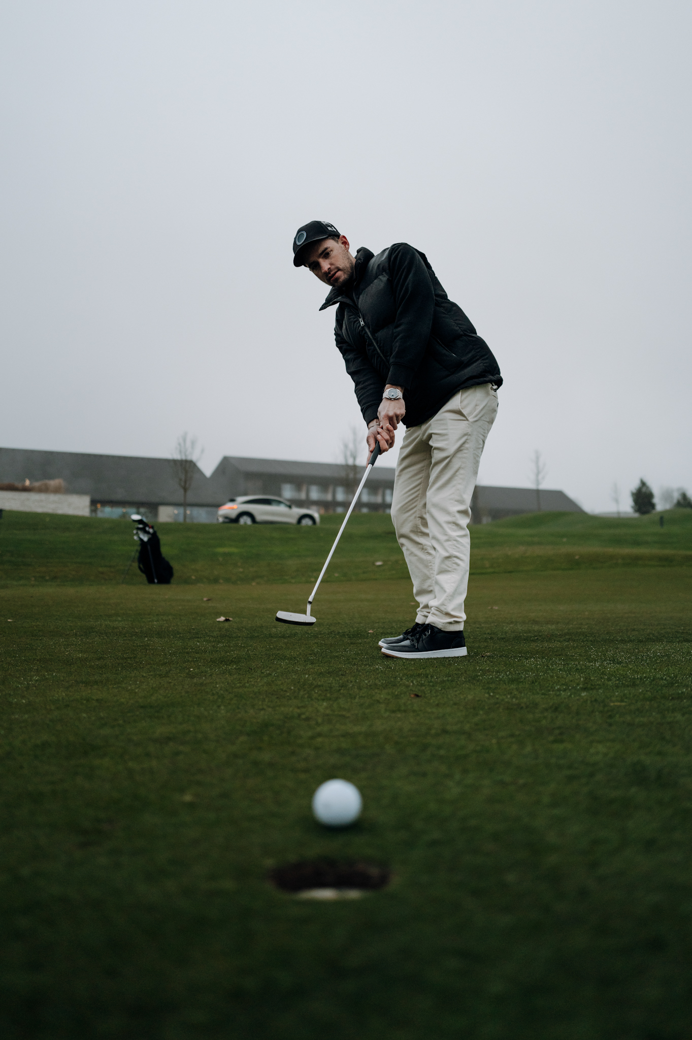 Man putting on a green, with the Smart #3 Premium in the distance.