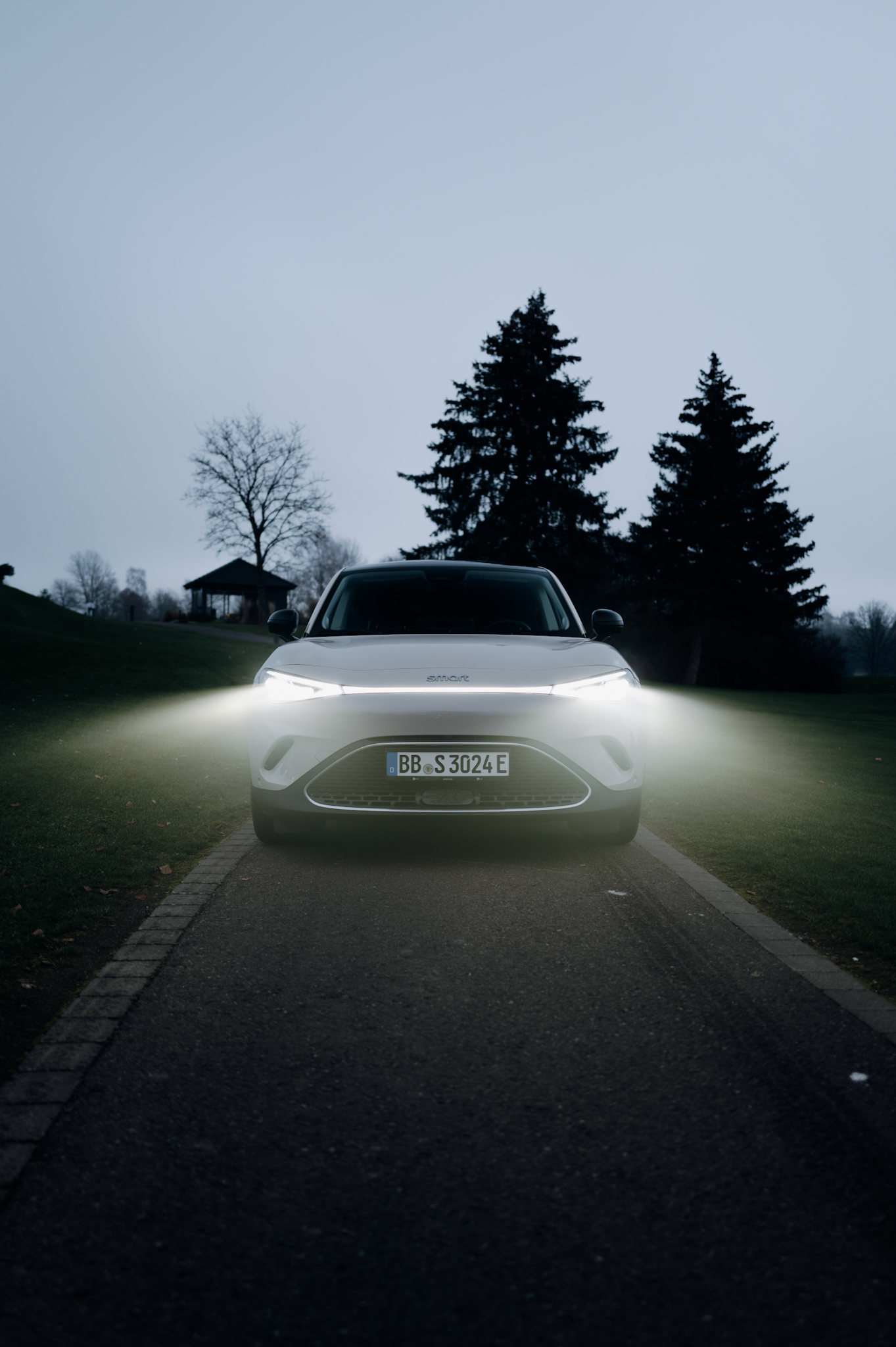 Smart #3 Premium with headlights on, parked on a golf course at dusk.